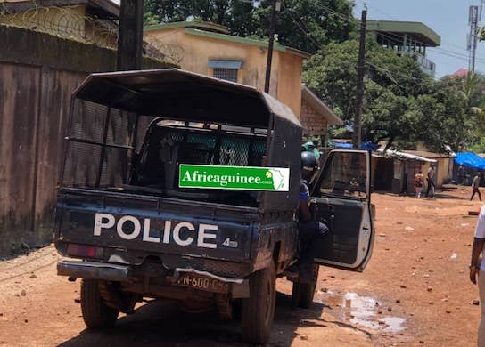 Un véhicule de la police face à des manifestants à Bambéto